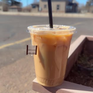 An iced coffee posed on the drive-thru windowsill with Vernal houses behind