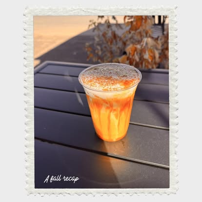 An orange seasonal drink on the patio table among fall leaves